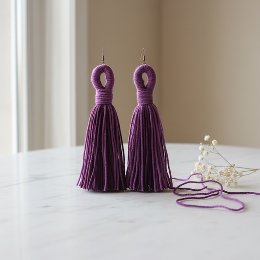 Purple tassel drop earrings styled on a white marble surface with professional lighting
